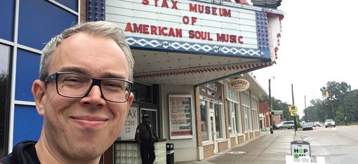 Person with blurred face in front of the Stax Museum of American Soul Music with distinctive marquee and street view.