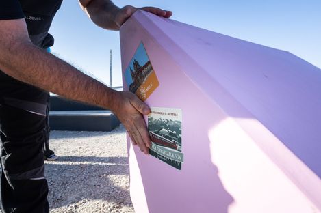 Close-up of a pink Enzi with travel stickers during installation on Mount Schafberg.