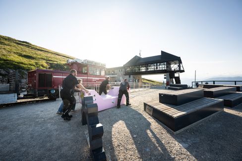 Several people position a pink Enzi on the viewing terrace at Mount Schafberg.