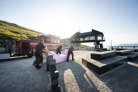Several people position a pink Enzi on the viewing terrace at Mount Schafberg.