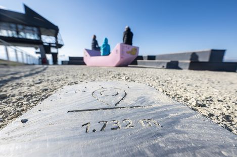 Pink Enzi on the viewing terrace of Mount Schafberg with visitors seated in the background.