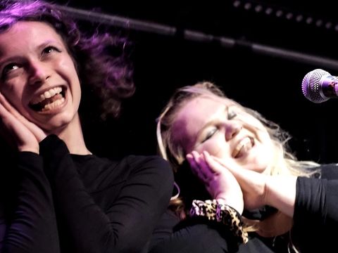 Zwei junge Menschen stehen singend auf der Bühne. Sie haben offensichtlich viel Spaß dabei.