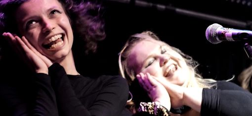 Zwei junge Menschen stehen singend auf der Bühne. Sie haben offensichtlich viel Spaß dabei.