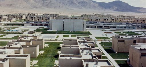 Im Vordergrund ist eine moderne Reihenhaussiedung zu sehen.
Im Hintergrund ragt ein Berg auf.