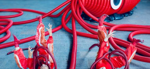 Zwei Performerinnen liegen mit dem Rücken auf dem Boden. Sie kämpfen gegen die Tentakel, die sie umschlingen.