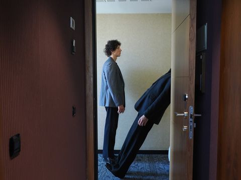 A view through the open door of a hotel room. One performer is standing upright; the other appears to be falling backward.