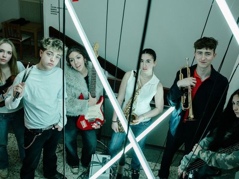 Sechs junge Menschen stehen mit ihren Instrumenten in einem Stiegenhaus.