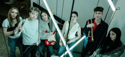 Sechs junge Menschen stehen mit ihren Instrumenten in einem Stiegenhaus.