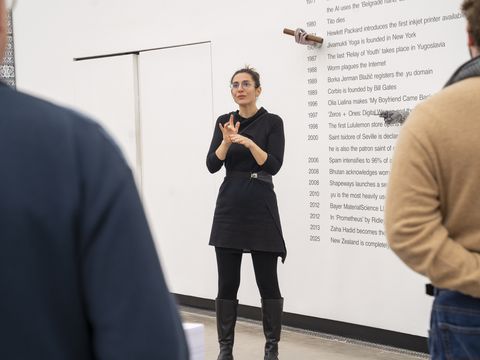 Eine Person steht im Ausstellungsraum vor einem Kunstwerk und verdolmetscht eine Führung in Gebärdensprache.