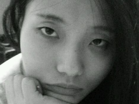 Portrait of a person with long hair resting their head on their hand.