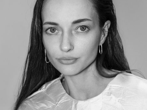 Woman with long straight hair wearing a shiny slightly wrinkled top.