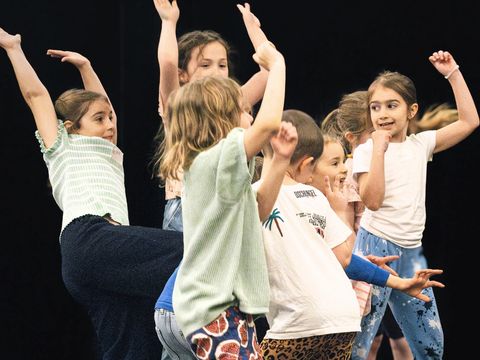 Several children are holding their arms in the air and dancing.