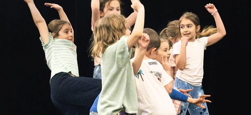 Several children are holding their arms in the air and dancing.