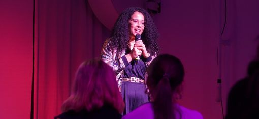 A person holding a microphone is speaking to the audience.