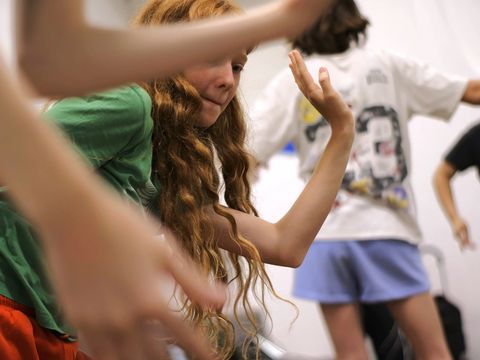 A girl with long hair is concentrating as she performs an unusual movement.