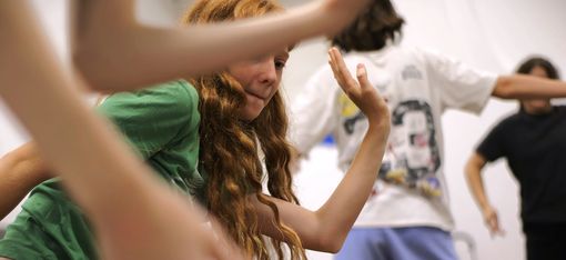 A girl with long hair is concentrating as she performs an unusual movement.