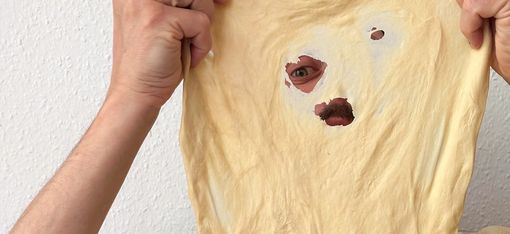 A person is looking through a hole in a piece of dough.