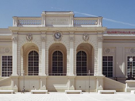 Außenansicht des Gebäudes der Halle E+G mit blauem Himmel und Bäumen links und rechts.
