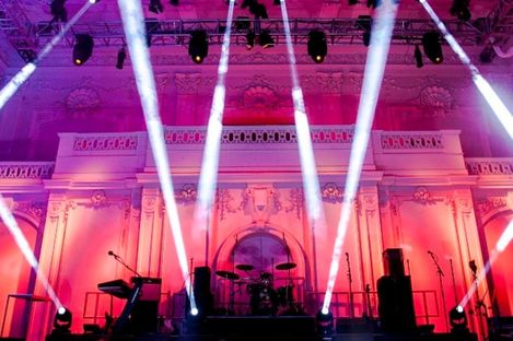 Concert stage with drums, speakers, and microphones in front of the historic architecture of Hall E+G in the MQ with atmospheric lighting.
