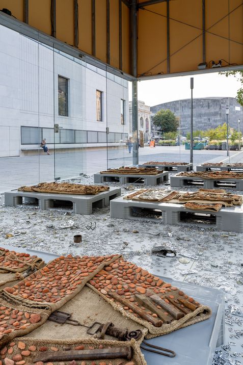 Installation featuring textile objects on platforms combined with metal parts and fragments, presented in the MQ Art Box.