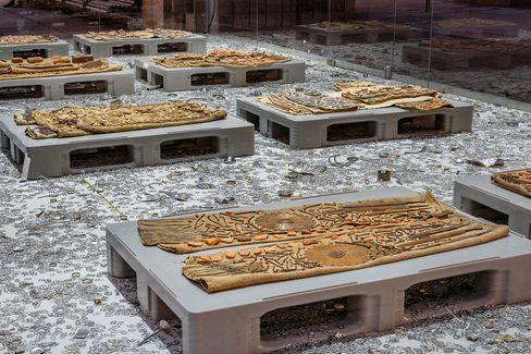 Interior view of the MQ Art Box showing an installation of textile works, metal objects, and scattered materials on the floor.