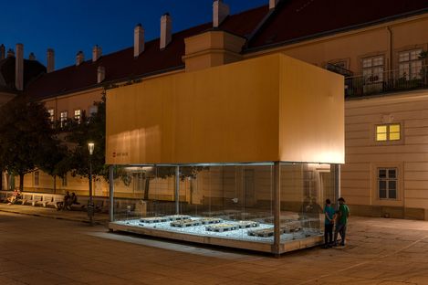 MQ Art Box at night with an illuminated installation of platforms and textile objects inside.