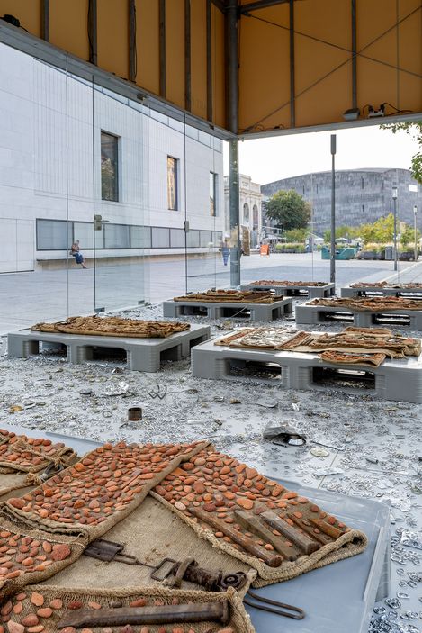 Installation featuring textile objects on platforms combined with metal parts and fragments, presented in the MQ Art Box.