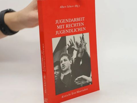 Hand holding a red book titled "Jugendarbeit mit rechten Jugendlichen" with a black-and-white photo of youths on the cover.