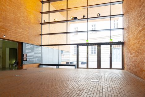 Brick foyer of the Kunsthalle Wien with large glass front, benches and the entrance to the exhibitions.